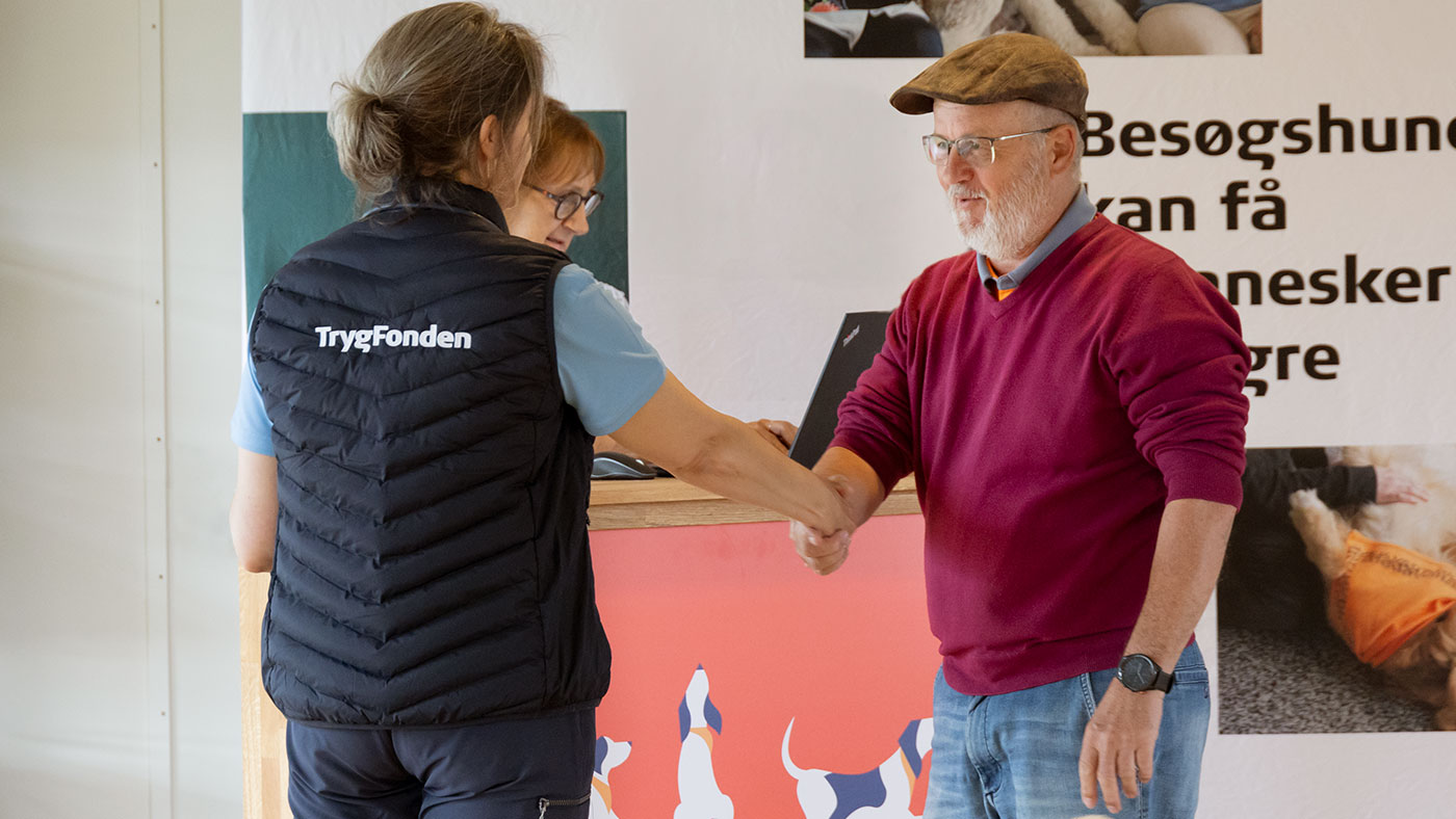 Dyrlæge fra TrygFonden Besøgshunde giver hånd til besøgshundeejer
